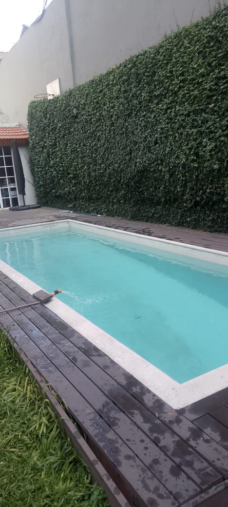 Piscina con deck de madera y vegetación